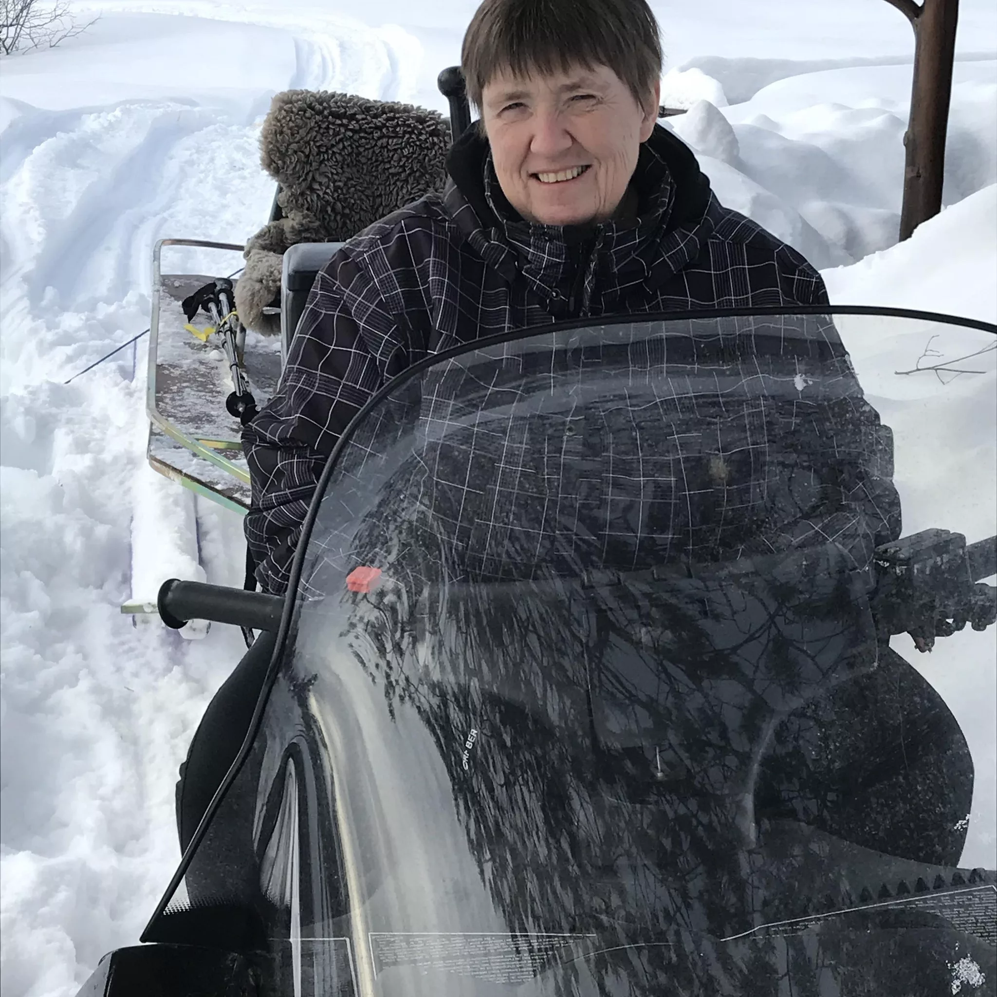 Bilde av Maya Haugan som sitter på en snøscooter. Mye snø i bakgrunn.