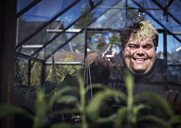 Portrettbilde av Aleksander Olsen, likeperson i MS-forbundet. Han sitter bak noen planter i et drivhus.