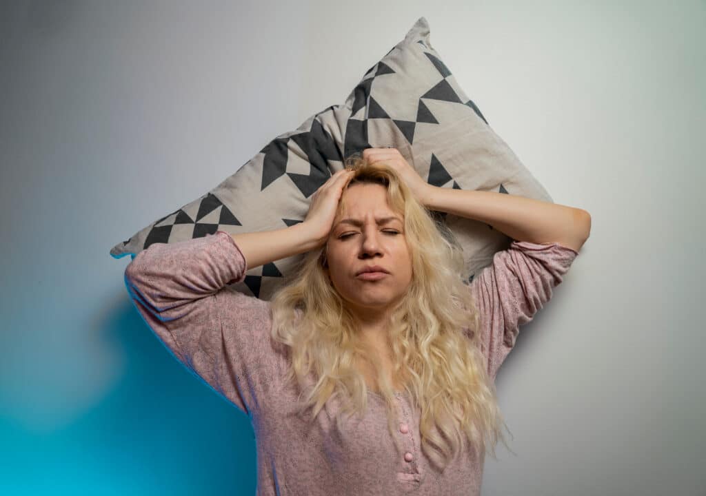 Illustrasjonsbilde som viser en blond kvinne som ligger og holder seg til hodet som om hun opplever et attakk.