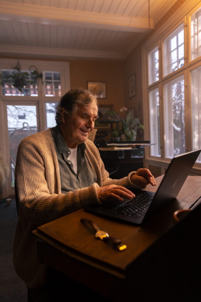 Bestefar sitter ved skrivebordet og skriver på datamaskinen