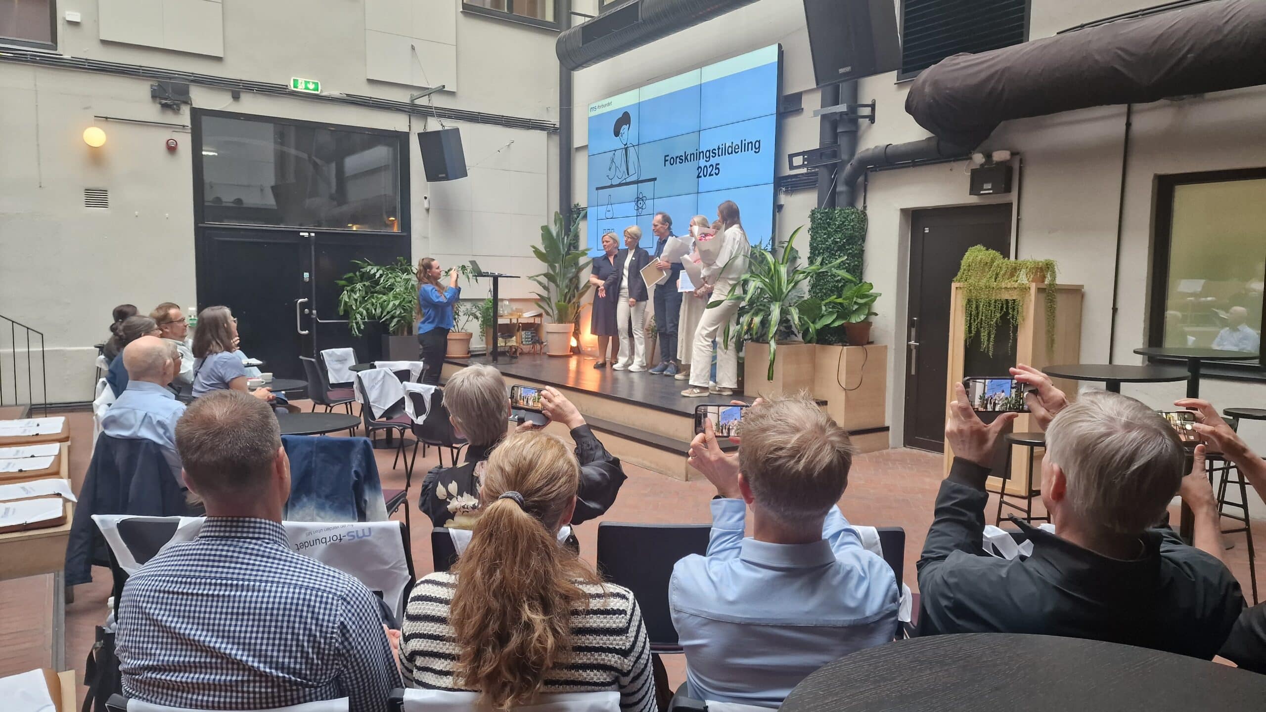 Forskere på scenen som mottar blomster og diplom under forskingstildelingen 2025
