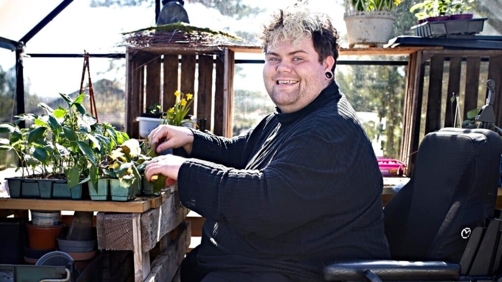 Bildet av Aleksander som planter i hagen, sittende i rullestol.