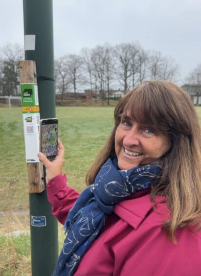 Bilde av Evy Martinsen, likeperson i MS-forbundet. Hun står foran en stolpe i forbindelse med stolpejakt.